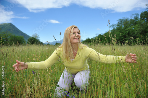 Pretty healthy summer woman outdoors on green field in Alps enjo photo