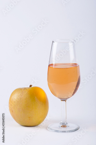 A glass filled with orange substance and an apple