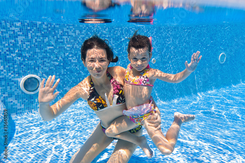 Underwater smiling family in swimming pool