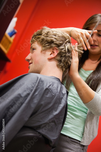 Portrait of a serious woman cutting a man's hair