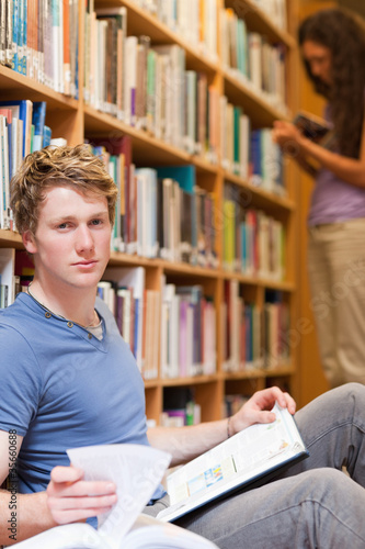 Portrait of a handsome student posing with a book while his clas