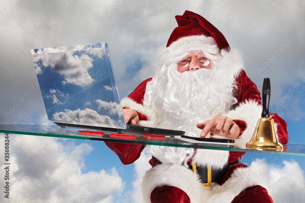 Santa Claus placing orders on his laptop and tablet-pc