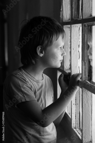 Sad boy looking in window. Black and white.