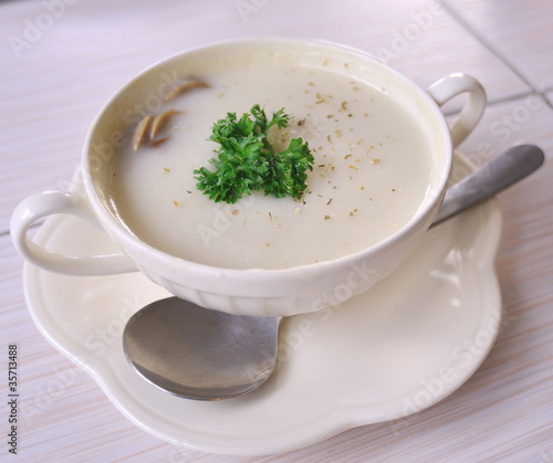 Mushroom soup with parsley in white ceramic bowl and spoon