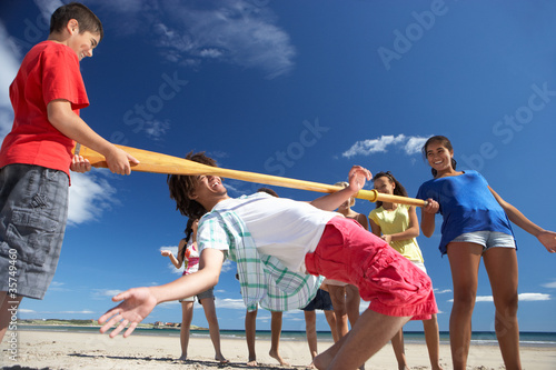 Teenagers doing limbo dance on beach