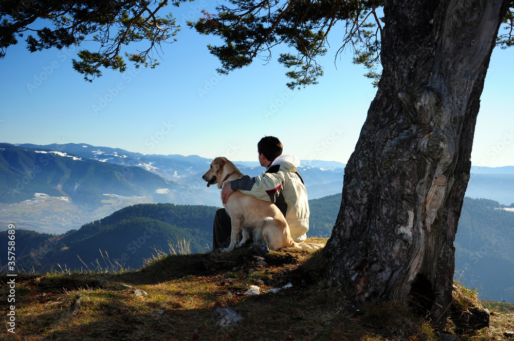 Young man enjoying mountain view with his dog