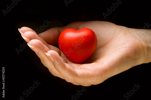 Heart in hand isolated on black background