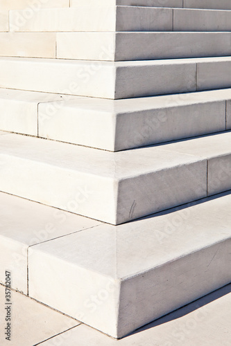 White marble stairs outdoors with shadows on right side.