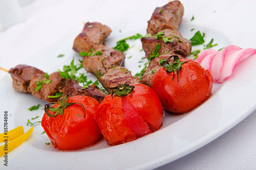 Kebab and tomatoes in the plate Kebab and tomatoes in the plate