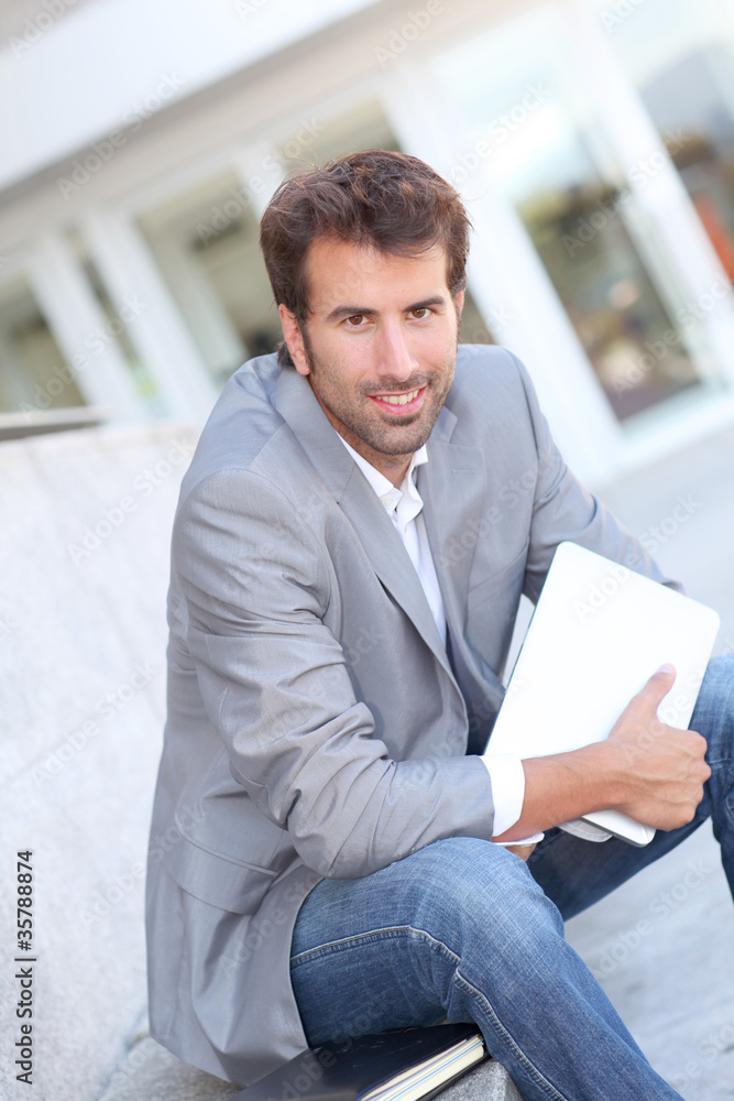 Relaxed businessman sitting outside with tablet Relaxed businessman sitting outside with tablet