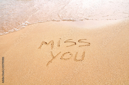 Miss you text written on the beach sand photo