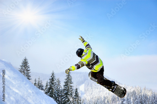 Snowboarder at jump inhigh mountains at sunny day