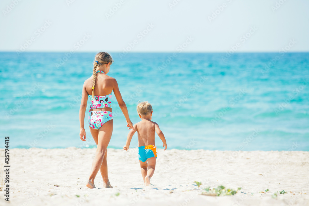 Young girl and boy playing happily at pretty beach