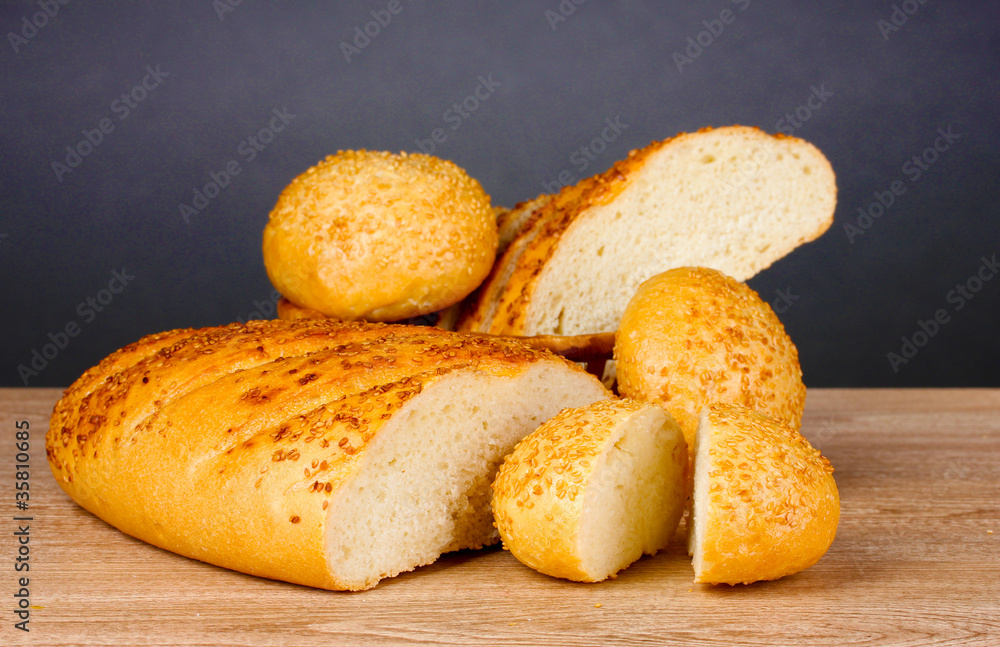 white bread and buns on wooden table on gray background