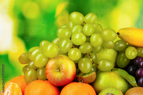 Ripe juicy fruits on wooden table on green background