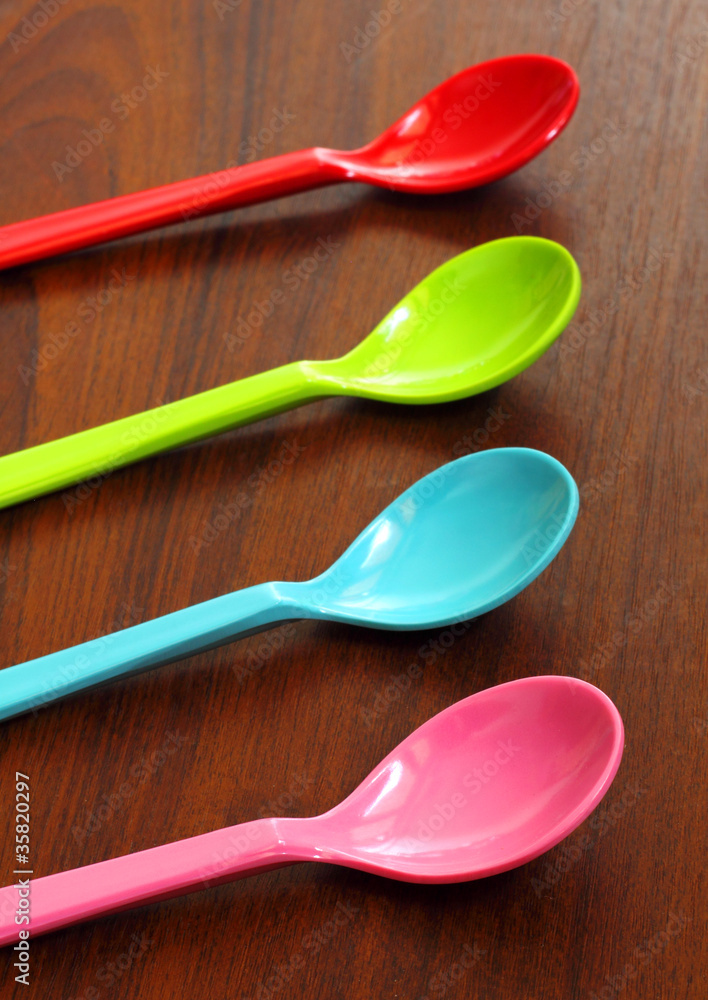 Colorful plastic spoons on wood background Colorful plastic spoons on wood background