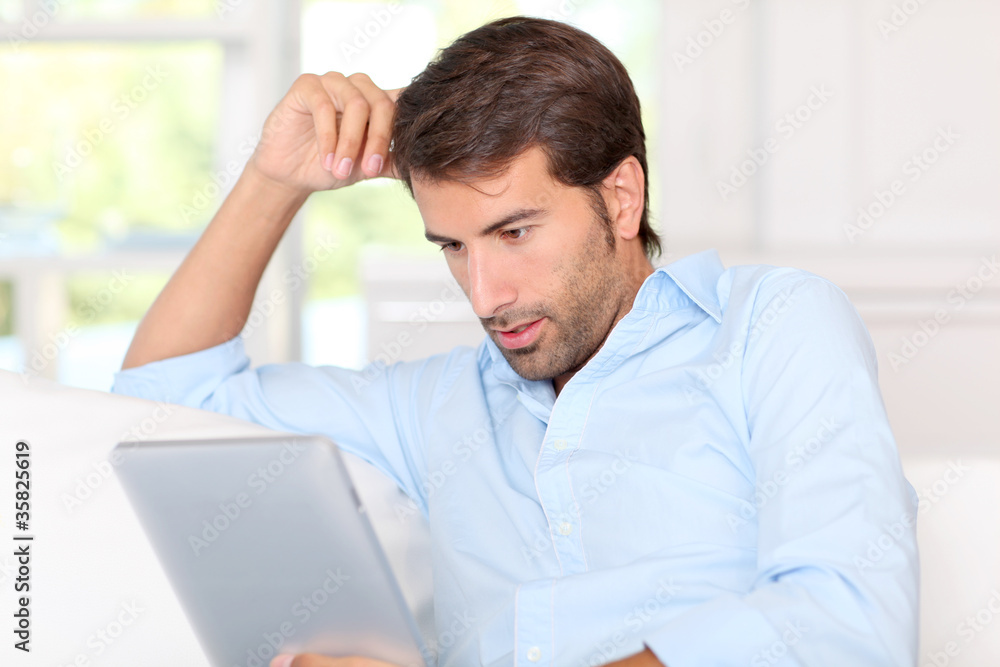 Handsom guy using electronic tablet at home Handsom guy using electronic tablet at home