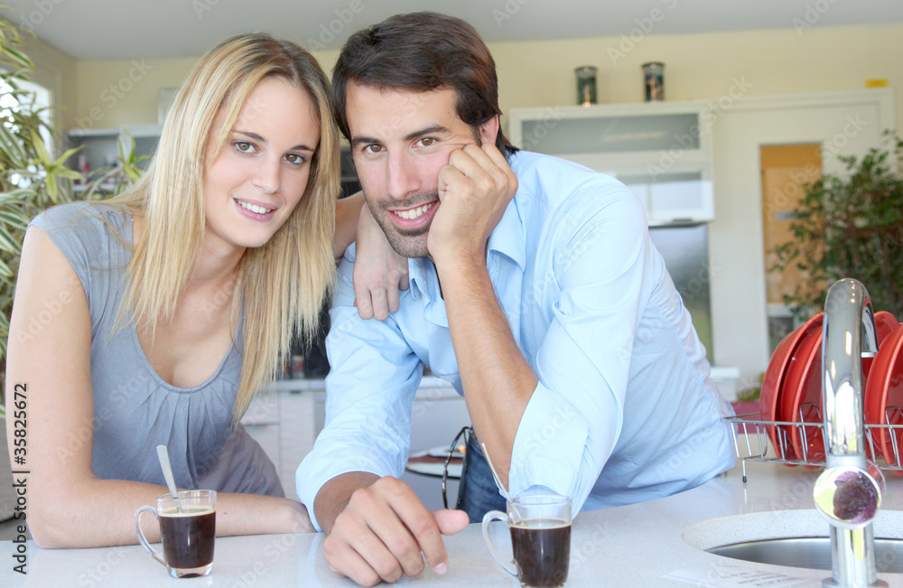 Happy young couple standing in home kitchen Happy young couple standing in home kitchen