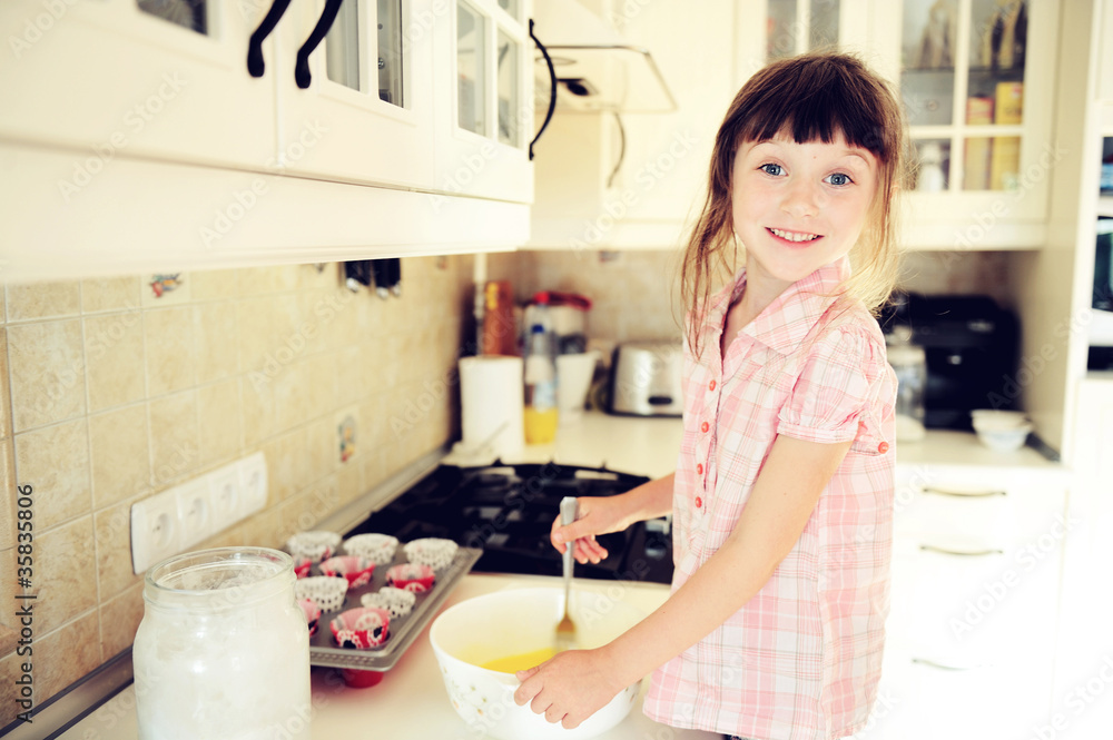 Happy child girl making muffins in kitchen Happy child girl making muffins in kitchen