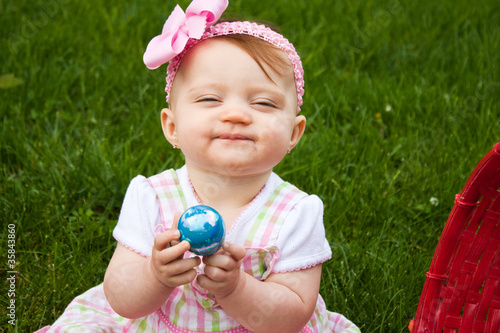 Small child holding a blue Easter egg while smirking