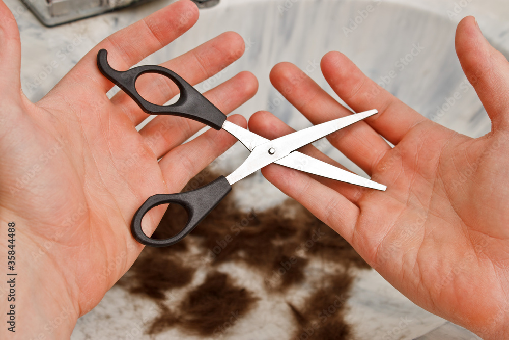 Person regretfully holding scissors with hair in the sink Person regretfully holding scissors with hair in the sink