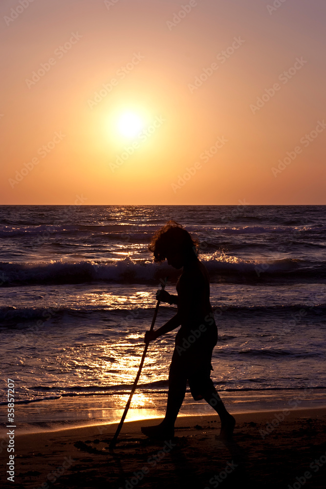 Young boy playing on the beach during sunset