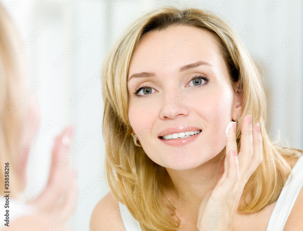 Beautiful woman applying cosmetic cream on face Beautiful woman applying cosmetic cream on face
