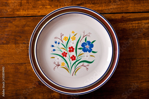 Top view of a stack of floral plates on a wooden surface