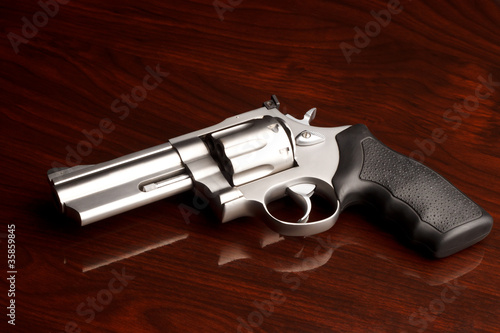 Clean .357 revolver laying on reflective wooden table photo