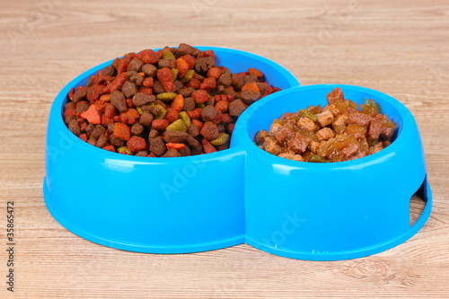 Dry cat food in bowls on wooden background