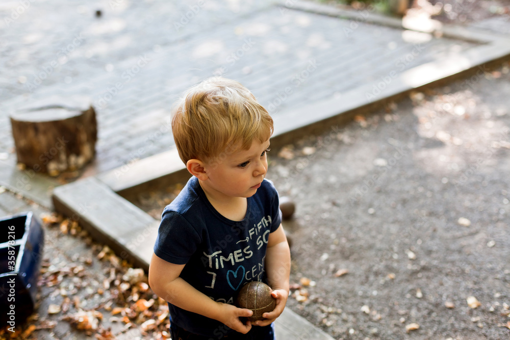 Baby boy with blond hairs playing petanque Baby boy with blond hairs playing petanque