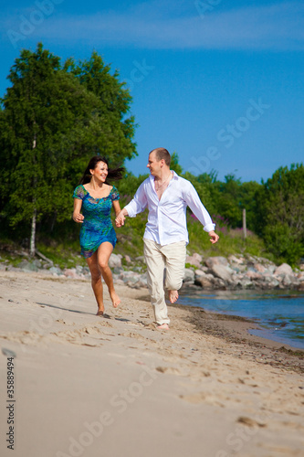 Enamored man and girl running along coast of sea