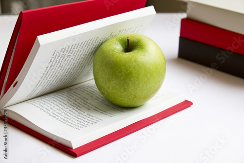 Tablou pe pânză Mela granny smith tra le pagine di un libro