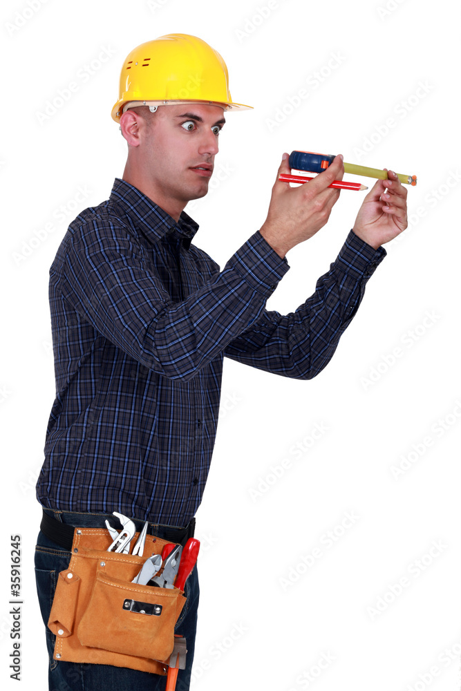 Man looking at his measuring tape surprisingly Man looking at his measuring tape surprisingly