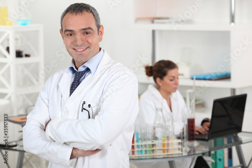smiling doctor cross-armed in lab