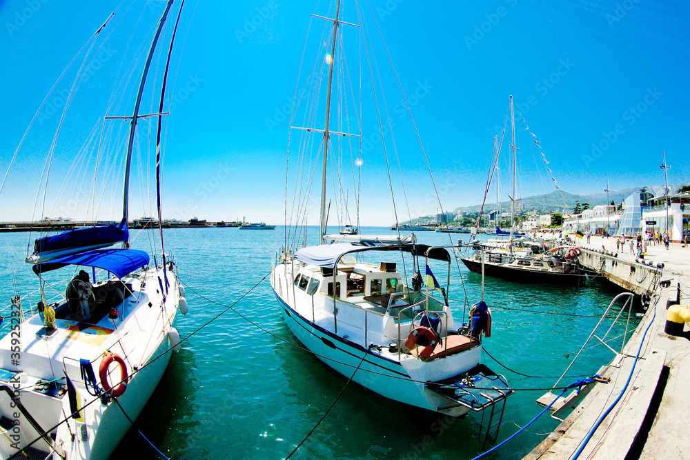 sailboats stand near pier in Yàltà