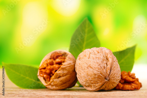 walnuts and leaves on wooden table on green background