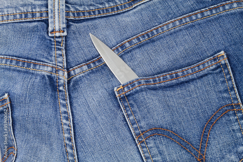 Knife blade showing out from a jeans back pocket