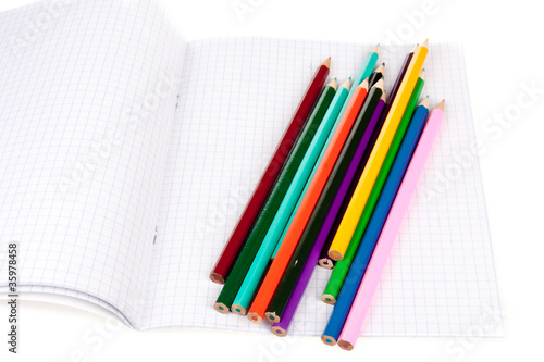 Exercise book with colored pencils isolated over white