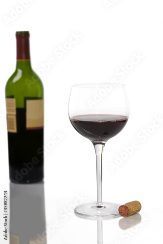 A Glass of Red Wine on White with Bottle in Background