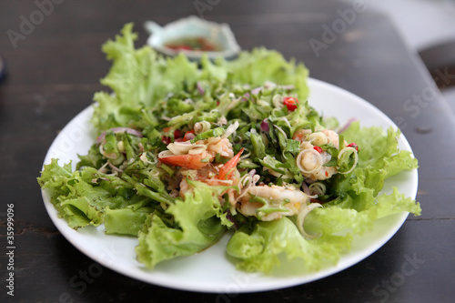 Thai dressed spicy salad with prawn and pork in wood background