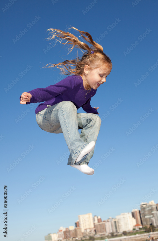 cheerful little girl jumping high in the blue sky cheerful little girl jumping high in the blue sky