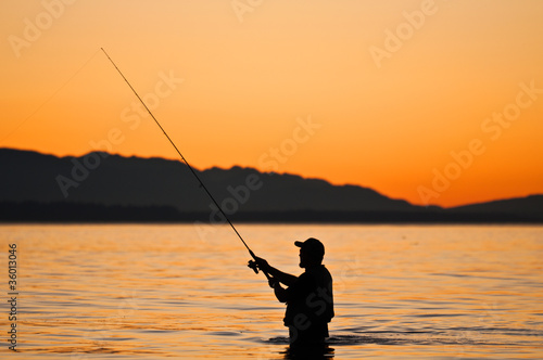Silhouette of a fisherman with a fishing pole at sunset.
