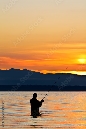 Silhouette of a fisherman with a fishing pole at sunset. © Garry L.