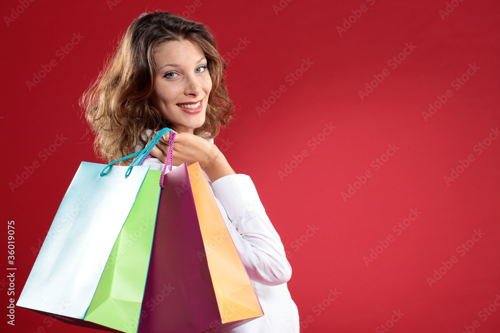 Woman holding shopping bags against a red background Woman holding shopping bags against a red background