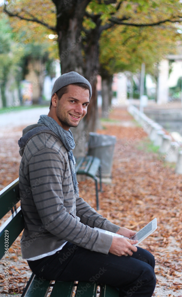 Fototapeta premium Man sitting on a Bench with netbook smiling
