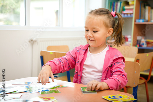 Cute little girl is playing with educational cards