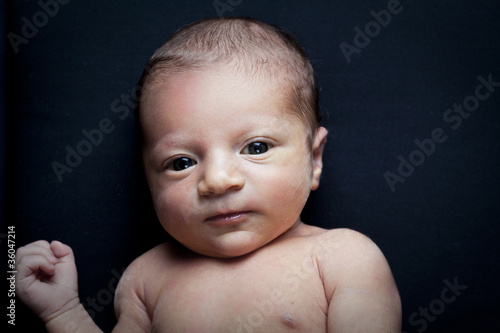 portrait of adorable newborn baby girl on black background
