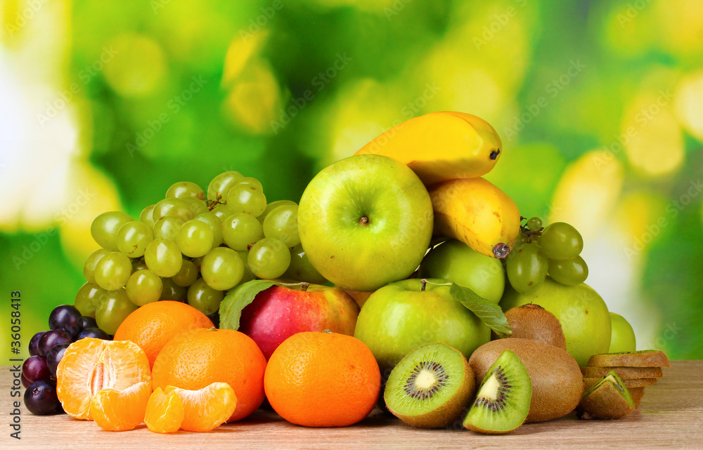Ripe juicy fruits on wooden table on green background Ripe juicy fruits on wooden table on green background