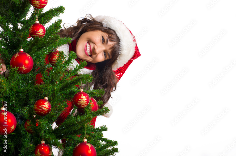 lachende Frau schaut hinter Weihnachtsbaum hervor